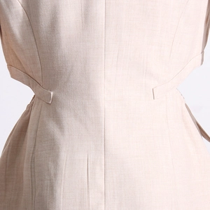 Détail du dos d'une veste beige présentant des découpes à la taille et tissu texturé