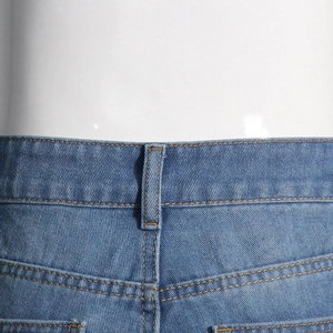 Détail de la taille d'un jean en denim avec coutures jaunes et passant de ceinture sur mannequin