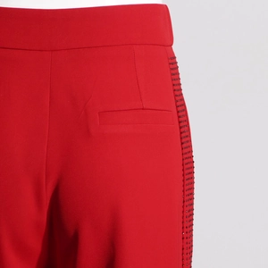 Detailed macro view of red high-waisted trousers with luxury side rhinestone stitching