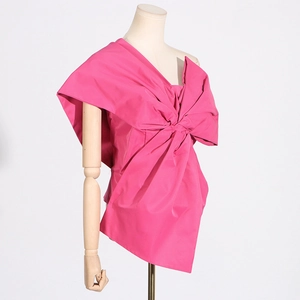 Detail of creative asymmetric top featuring a large hot pink 3D bow and satin texture
