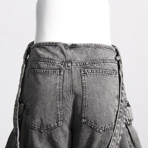 Detail of grey washed denim jeans back waist with functional pockets and long straps