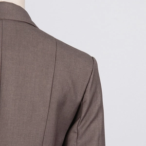 Detailed view of coffee brown blazer featuring precision shoulder tailoring and woven fabric
