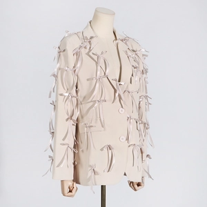 Detail shot of beige blazer with 3D ribbon bows, notched lapels and dual buttons