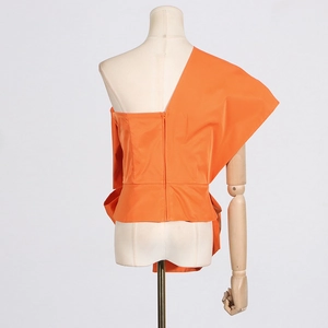 Detail view of bright orange asymmetric top with back invisible zipper on mannequin