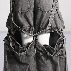 Detail of dark gray washed denim cargo pants with cut-out knees and multi-pocket design