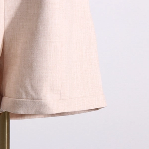 Détail du tissu du blazer rose clair montrant les coutures et la texture lisse