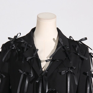 Detail of black blazer featuring 3D satin bow embellishments and classic lapel design