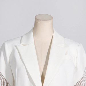 Dettaglio del blazer bianco con maniche in pizzo traforato e design a rete raffinato