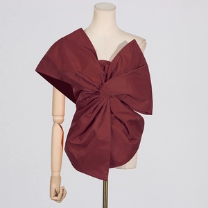 Detail view of large dark red bow tie design on asymmetric women's woven top fabric