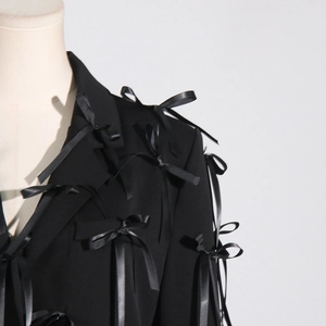 Detailed view of black blazer featuring layered 3D satin bows and elegant long ribbons