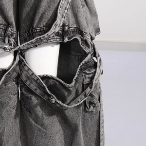 Detailed close-up of dark grey washed denim fabric featuring creative hollow-out cutouts