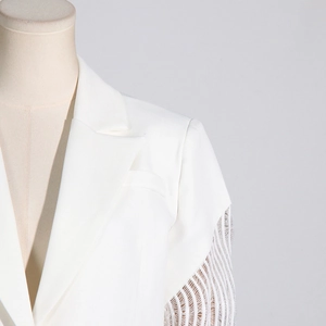 Dettaglio del blazer bianco con rever a V e intricata trama delle maniche in rete traforata