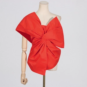Detail of red oversized bow decoration and asymmetric tailoring on women's top