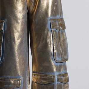 Détail du tissu denim doré à effet brillant et des grandes poches cargo de ce pantalon