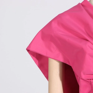 Close-up of fuchsia top showing elegant 3D pleat details and premium woven fabric