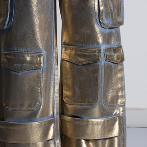 Gros plan détaillé sur le pantalon cargo doré à multiples poches et texture métallique
