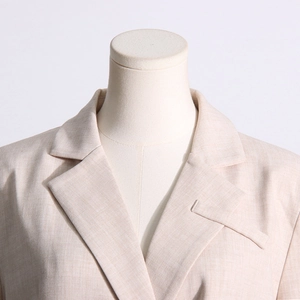 Détail du revers et texture du tissu fin sur la veste de blazer beige professionnelle