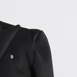 Detailed shoulder view of a black blazer dress featuring padded design and crystal accent