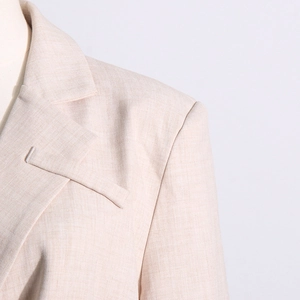 Détail du blazer beige clair avec col à revers, épaulettes et texture en lin