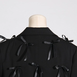 Detail view of stylish black blazer back featuring elegant satin bow tie decorations