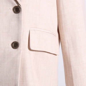 Détail d'un blazer beige clair avec texture lin et boutons tissés en métal chic