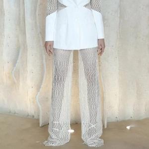 Détail d'un ensemble blazer blanc avec mesh à vagues transparent et pantalon à jambes larges
