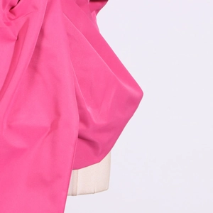Detail of glossy rose pink satin fabric showing elegant texture and bow construction