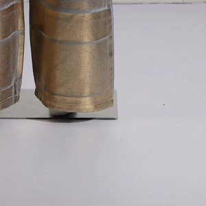 Détail du pantalon cargo doré métallisé avec motif à carreaux bleus et coutures d'ourlet