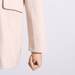 Détail du blazer beige présentant la texture tissée et le rabat de la poche latérale