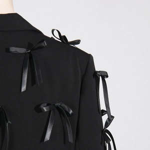 Detail of black blazer featuring 3D satin bow embellishments on sleeves and shoulder