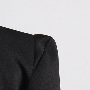 Close-up of structured shoulder and glossy satin fabric on a black blazer dress