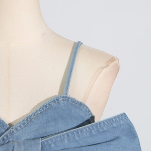 Detailansicht des hellblauen Denim-Tops mit Kontrastnähten und Schleifen-Design am Saum