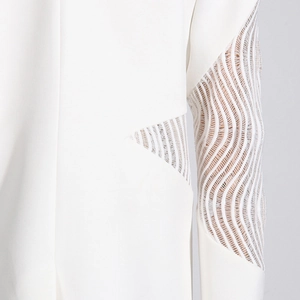 Dettaglio blazer bianco con intricato pizzo traforato sulle maniche e sul fianco