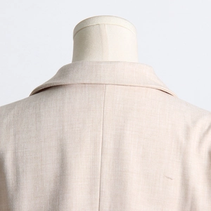 Gros plan sur la couture du col et la texture du tissu d'un blazer de costume beige