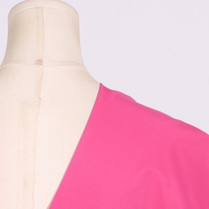 Detailed view of the asymmetrical neckline and bow tie decoration on a pink blouse