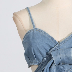 Nahaufnahme des blauen Denim-Oberteils mit V-Ausschnitt und gelben Kontrastnähten