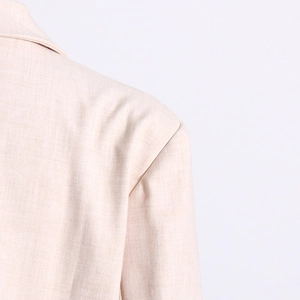 Vue détaillée de la couture d'épaule et de la texture tissée de ce blazer beige chic