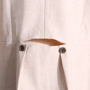 Gros plan détaillé du tissu blazer crème avec boutons métalliques et découpe