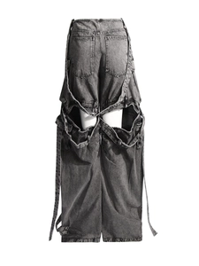 Back view of deconstructed gray wash jeans with multi-pocket cutouts and layered straps