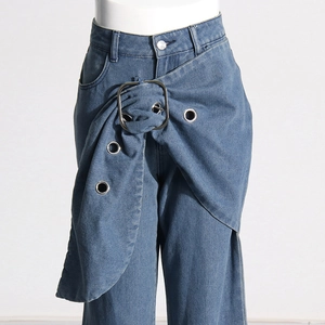 Detailed close-up of asymmetrical wrap waist design and metal buckle on blue jeans