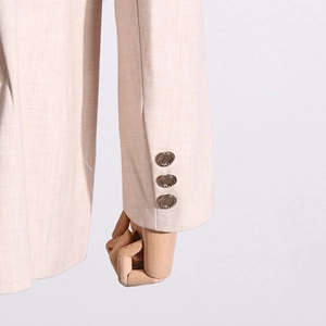 Détail de la manche d'un blazer beige clair avec trois boutons ronds sur tissu tissé