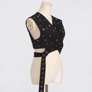 Detail of black punk style vest featuring metal eyelets and adjustable waist strap