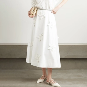 Detailed close-up of 3D floral embroidery and premium cotton texture on white A-line skirt