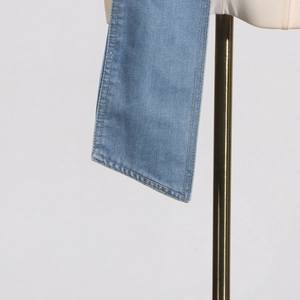 Nahaufnahme von hellblauem Denim-Stoff mit präziser gelber Steppnaht am Träger