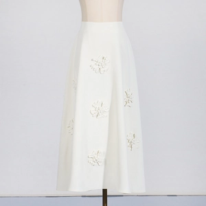 Detail of elegant white A-line skirt with 3D floral appliques and high-waisted design