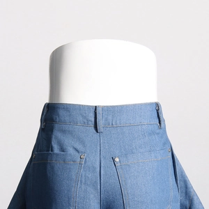 Détail d'un jean bleu taille haute avec poches arrière et rivets métalliques argentés