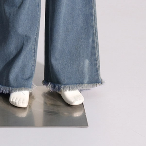 Detailed close-up of blue wide-leg denim jeans featuring stylish raw fringe hem edges