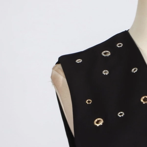 Detailed close-up of silver metal eyelets on a black sleeveless trendy vest's shoulder