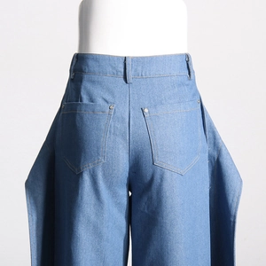 Détails du jean bleu taille haute avec des clous argentés et des coutures contrastées