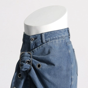 Detail view of the waist pleats and silver metal buckle on these blue denim pants